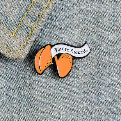 Enamel pin with cartoon fortune cookie dripping oil — side view