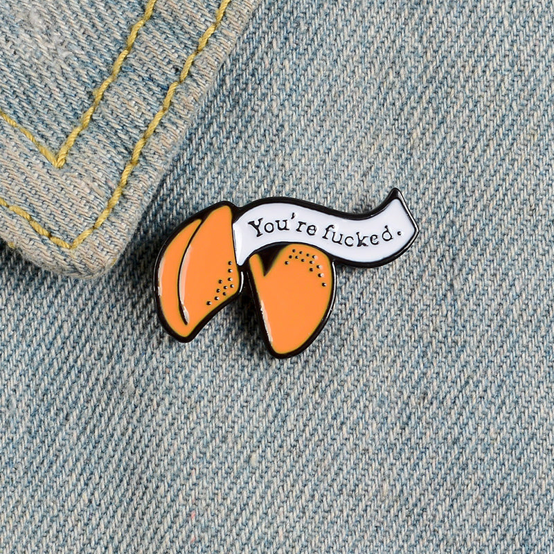 Enamel pin with cartoon fortune cookie dripping oil — side view