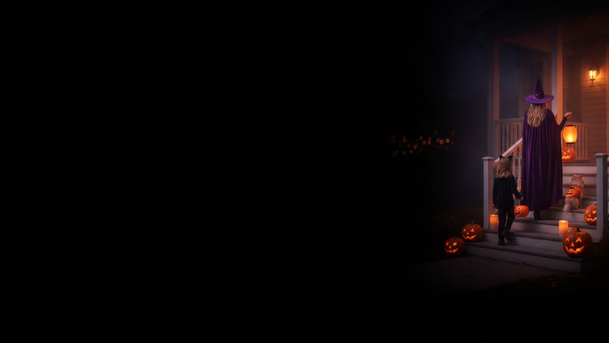 A witch, a child in a black-cat costume and a dog dressed as a pumpkin climb lit porch steps at dusk